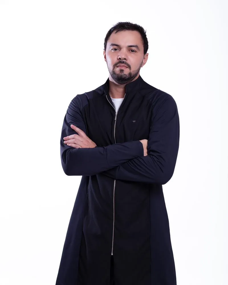 Dr. Firminio Humberto em pé, de braços cruzados, de camisa branca