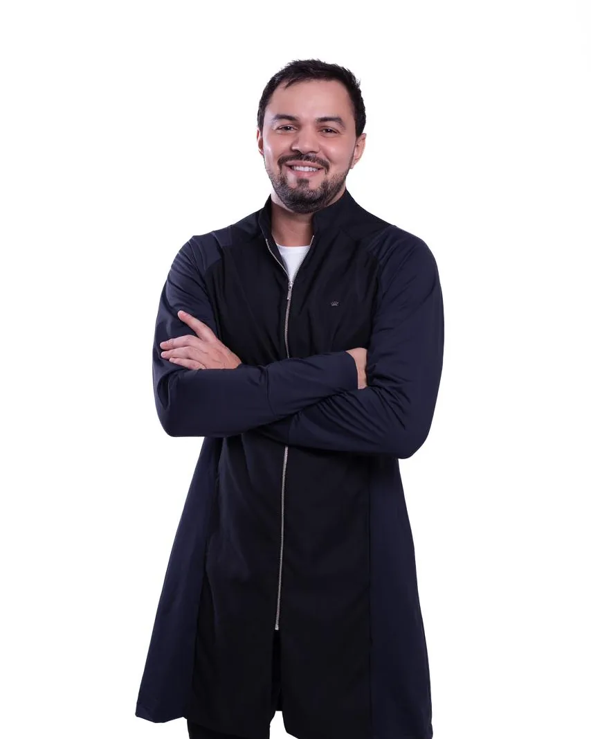 Dr. Firminio Humberto em pé, de braços cruzados, de jaqueta escura